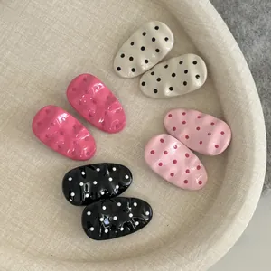 Close-up of pink polka dot pattern and wavy resin texture on metal hair clips set