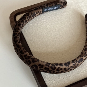 Close-up of velvet leopard print headband with a handmade label on a vintage tray