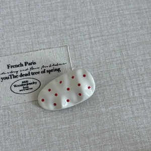 Close-up of pink polka dot hair clip with wave texture on a vintage linen background