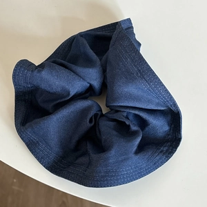 Detail of blue denim scrunchie with triple parallel stitching and soft fabric pleats