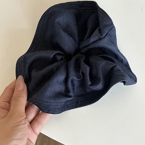 Detailed close-up showing the dark blue denim fabric texture and ruffles of this scrunchie
