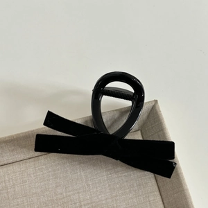 Elegant French black velvet bow claw clip for women on a cream beige display tray