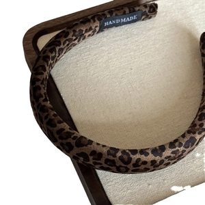 Elegant leopard print suede padded headband with handmade label on beige linen background