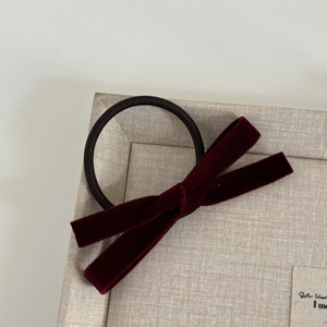 Detail shot of a deep burgundy velvet bow hair tie with high-elastic black rubber band