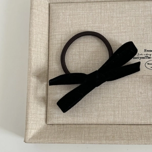 Close-up of a black velvet bow hair tie with a soft texture on a display card