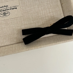 Detail shot of a black velvet bow hair clip with a vintage gold metal center accent