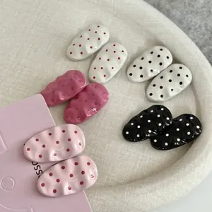 Pink polka dot wavy oval hair clips set for women on a beige fabric tray