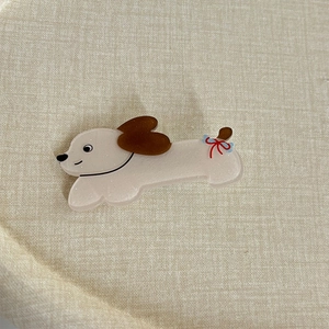 Détail d'une barrette chien blanc crème avec paillettes brillantes et un nœud en soie