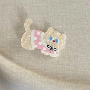 Gros plan sur la barrette chat en crème nacré et rose avec yeux bleus sur lin