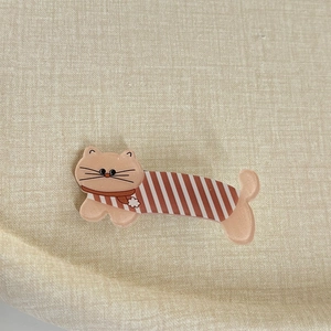Détail d'une pince à cheveux chat avec pull à rayures rouges et écharpe à fleurs