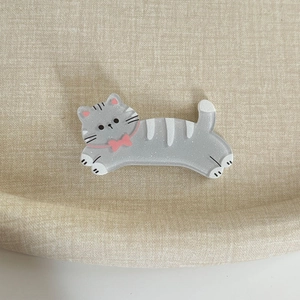 Vue macro d'une barrette chat grise pailletée avec nœud rose sur fond en lin beige