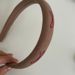 Detail view of retro mocha brown velvet padded headband with red bow embroidery