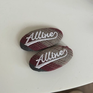 Detail of red and brown plaid hair clips featuring white Allure word embroidery