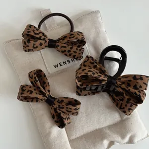 Detail view of leopard print bow hair clips and scrunchies set on textured linen fabric