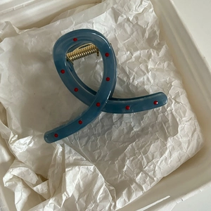 Pinza per capelli blu francese a pois rossi con molla dorata su carta stropicciata