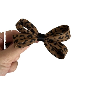 Leopard print bow hair clip with brown and black fabric pattern on white background