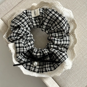 Detail of checkered hair scrunchie with lace edge, black ribbon bow and pearl bead