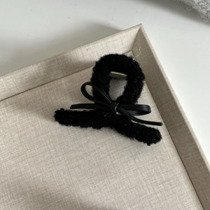 Fuzzy black fleece shark hair claw clip with a leather bow and gold metal spring