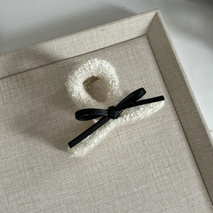 Detail of tweed hair claw with black leather bow accent and strong metal spring