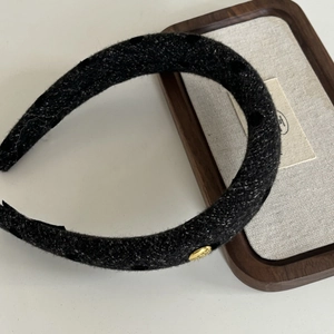 Detail view of thickened black wool headband with polka dots and gold button accent