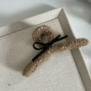 Detail view of large brown tweed hair claw clip with black leather bow accent
