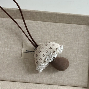 Detail eines Plüsch-Pilzanhängers mit beigefarbener Baumwollkappe und weißer Spitze