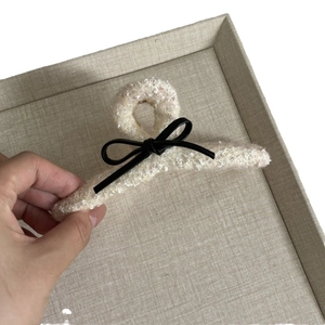 Elegant cream plush shark hair claw clip with black bow detail held for size demonstration