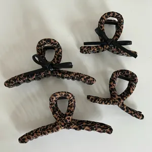 Detailed view of leopard print hair claw clips with fabric wrap and black bows