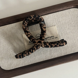 Leopard print fabric covered hair claw clip for women on a rustic wooden tray