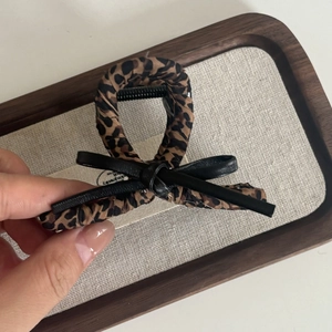 Leopard print hair claw clip with black leather bow detail and fabric wrapped design