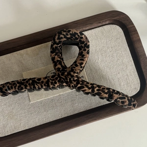 Close-up of leopard print fabric wrapped hair claw clip on a wooden display tray