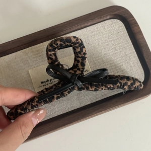 Detail view of large leopard print fabric claw clip with a black ribbon bow decoration