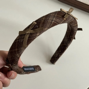 Detailed view of the handmade label and texture on the brown plaid bow headband