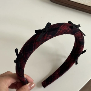 Detail of red and black plaid headband with multiple small black bows in academy style