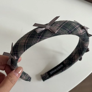 Close-up of handmade green plaid headband with satin bows and quality fabric texture