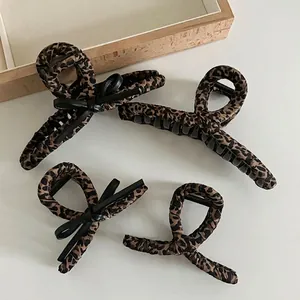Leopard print hair claw set with black bows on a minimalist wooden tray display