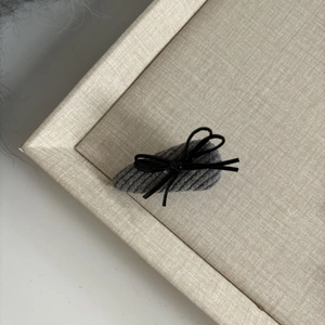 Close-up of grey knitted fabric hair clip with a small black ribbon bow detail