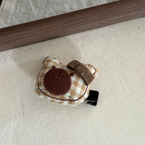 Nahaufnahme der niedlichen gelb karierten Bären-Haarklammer mit brauner Schleife und Clip