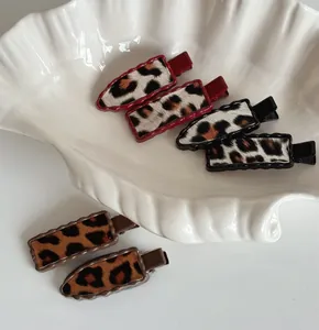 Détail de six barrettes à motif léopard en rouge, noir et marron sur un plateau décoratif