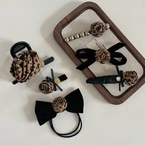 Detailed close-up of leopard rose hair accessories set with pearls and velvet bows