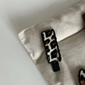 Pince à cheveux rectangulaire léopard avec bords ondulés noirs sur toile beige