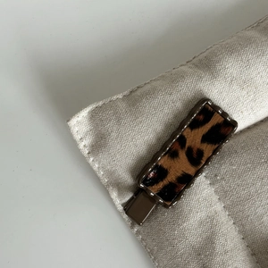Vue détaillée d'une pince à cheveux léopard avec bordure festonnée marron sur toile