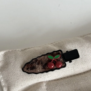 Detailed macro view of cute plush leopard print hair clip with red cherry accents