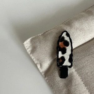 Détail macro du motif léopard sur tissu fixé sur une base de pince à cheveux noire
