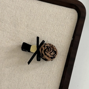 Detail of leopard print fabric rose hair clip with black ribbon bow and velvet grip