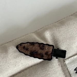 Detail showing the leopard print plush texture and duckbill clip design on the hair pin