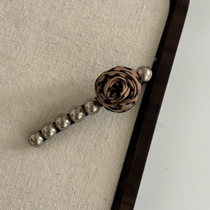 Macro detail of leopard print rose hair clip with metallic silver bead accents