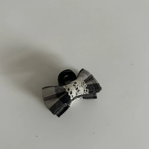 Detail of checkered bow hair clip with white lace trim and black plastic claw