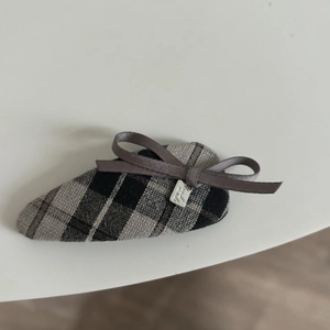 Detail of British plaid gray hair clip with dark ribbon bow and metallic charm