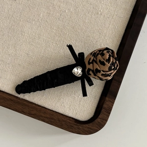 Detail of leopard print rose hair clip with heart rhinestone and black silk bow decor